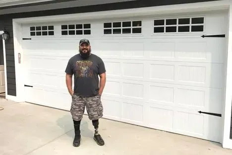 Customer standing in front of the white carriage-house garage door A-1 installed
