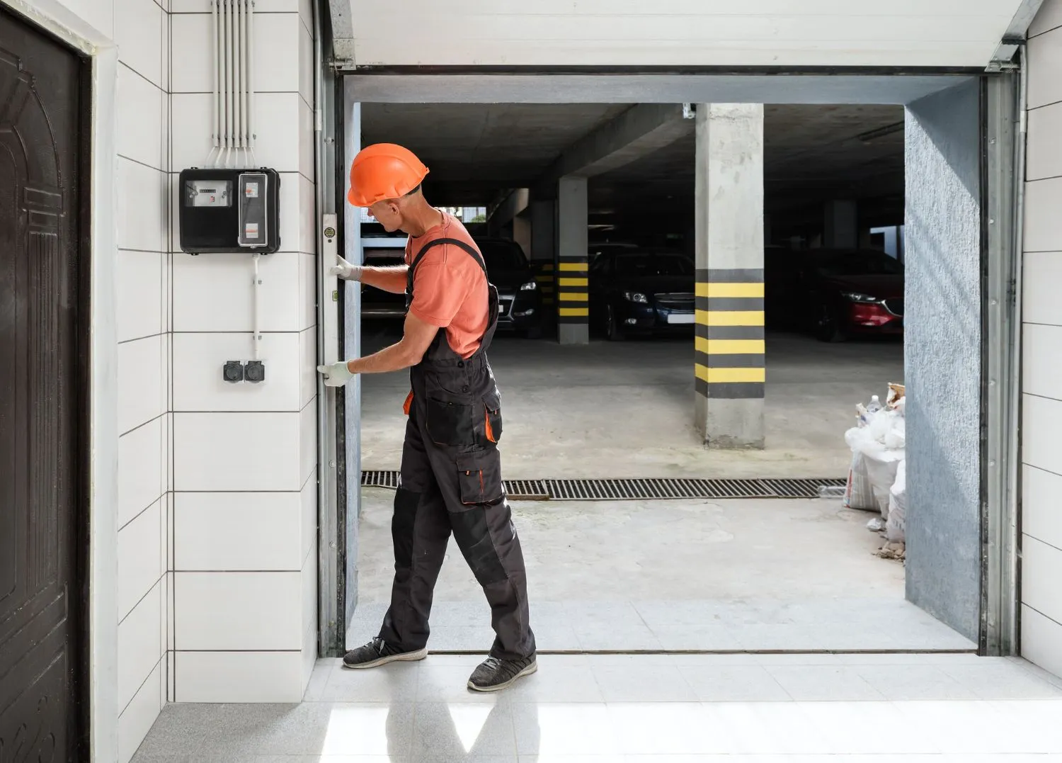Technician in a hard hat checking a garage door frame with a spirit level