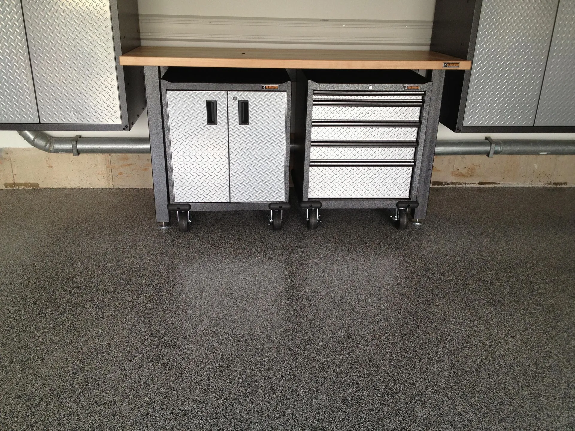 Garage workbench with diamond-plate tool cabinets above a speckled epoxy floor